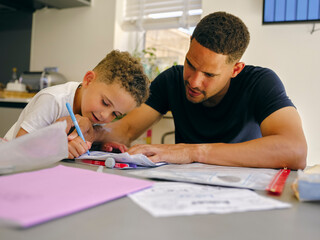 Naklejka premium Father assisting son doing homework at home