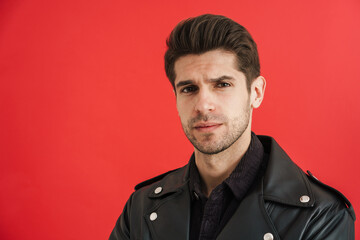 Young unshaven man wearing leather jacket looking at camera