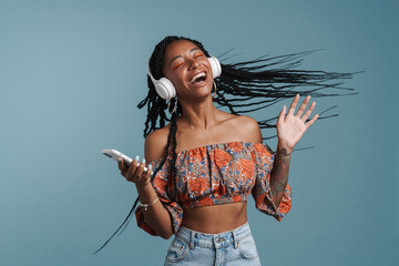 Young black woman singing while listening music with headphones