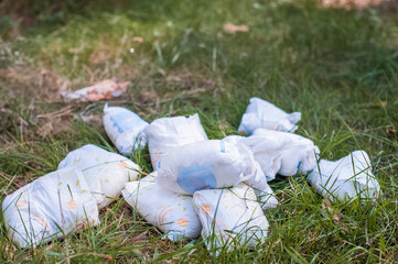 Diapers waste, dirty diapers in nature. Disposing of used baby nappies. Environmental Impact of Disposable Diapers. Pollution of the environment, soil and water.