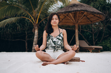 Asian woman at the beach practicing yoga