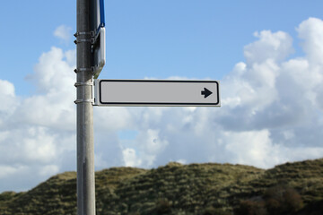 A signpost showing the way against a cloudy sky. In the signpost there is room for an editor to place a text.