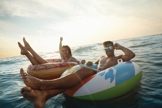 Happy couple with inflatable rings in sea