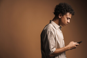 Black man wearing shirt using mobile phone while posing in profile