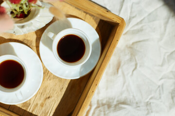 Breakfast in bed, try with two cups coffee and flower in sunlight at home, chambermaid bringing tray with breakfast in hotel room, good service
