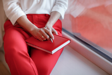 cropped photo of young European businesswoman with notebook is sitting by the window. Concept of...