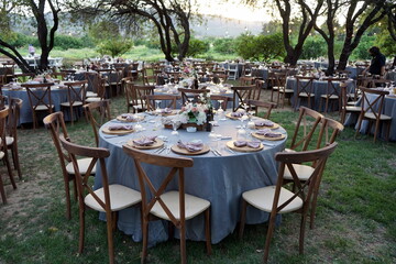 Runder gedeckter Tisch mit Blumenschmuck und alten Holzstühlen für eine türkische Hochzeit im...