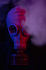 Man with a gas mask in a dark place with smoke and purple-blue lights