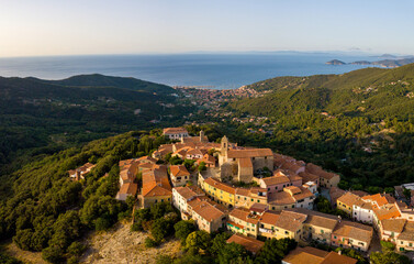 Aerial Drone Panorama of mountain old town Marciana on the islands of Elba Italy with green trees and the mediterranean sea ocean in the background