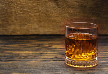 Whisky or whiskey or bourbon with ice on wood background