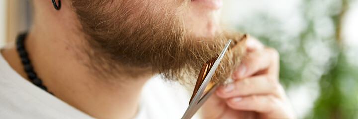 Banner Close up of Handsome man in white t-shirts cutting beard, moustache personally himself