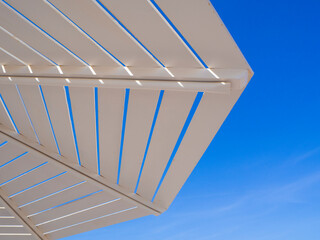 White wooden beach umbrella against the blue sky background