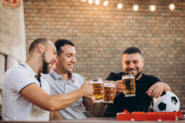 Friends drinking beer together at pub and watching football