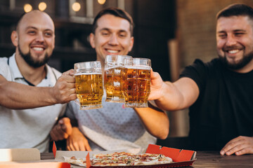 Friends drinking beer together at pub and watching football