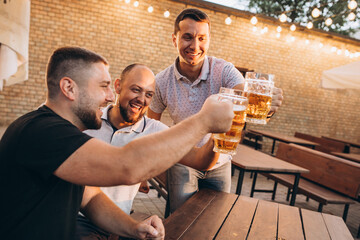 Friends drinking beer together at pub and watching football