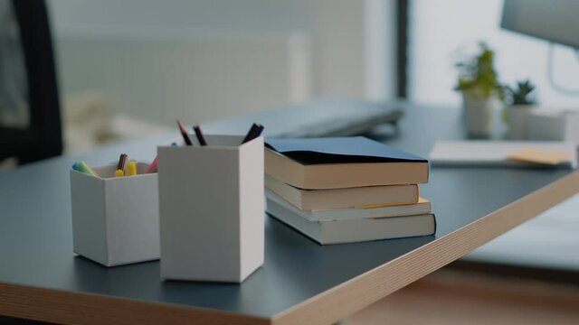 Close up of books and computer with keyboard on desk. Nobody in space for learning and homework with notebooks and pens on table. Empty home office with school supplies