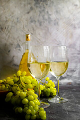 glass of wine, bottle, grapes on a concrete background
