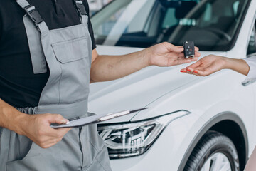 Woman at acr service station checking her car with mechanic