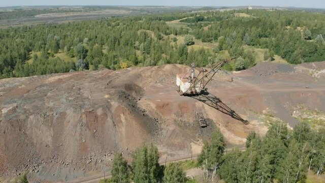 The yellow dragline fills the bucket with iron ore and turns. Development of a mineral deposit. Mining business.