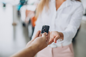 Woman receiving keys from car in a car showroom