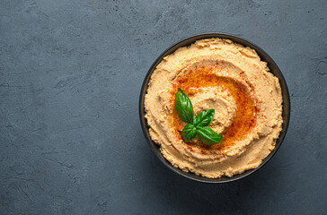 Traditional hummus with paprika and olive oil on a dark background. Top view, copy space.
