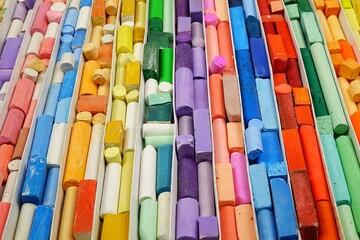 Obraz premium Multi-colored crayons for drawing are stacked in rows by color, background