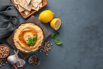 Obraz na płótnie Canvas Hummus and ingredients on a dark background. Oriental, healthy food. Top view, copy space.