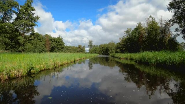 Nature scenery at the Weerribben-Wieden National Park in Overijssel the Netherlands, POV sailing through treed and forest