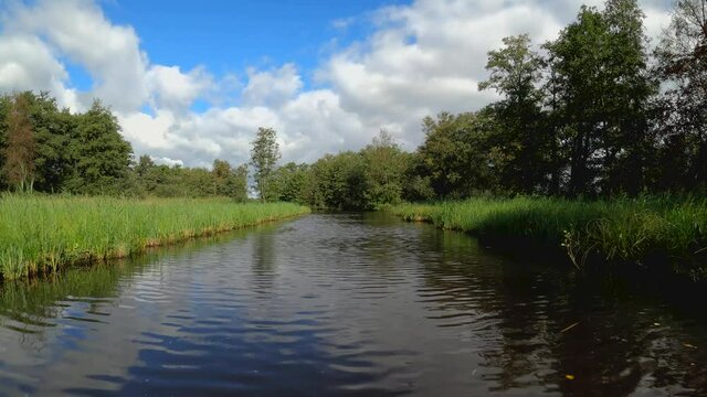 Nature scenery at the Weerribben-Wieden National Park in Overijssel the Netherlands, POV sailing through treed and forest