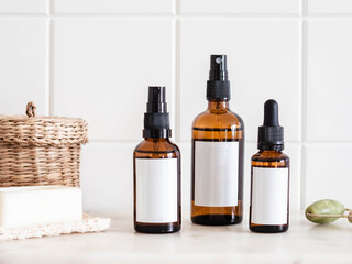 Mockup for care cosmetics products - amber bottles with white labels and various accessories on white marble shelf