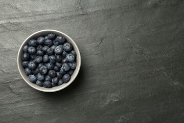 Ceramic bowl with blueberries on black table, top view and space for text. Cooking utensil