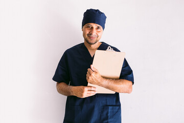 Male nurse, doctor or veterinarian in blue uniform at a window in a hospital, holding a folder with a report. Medicine, hospital and healthcare concept.