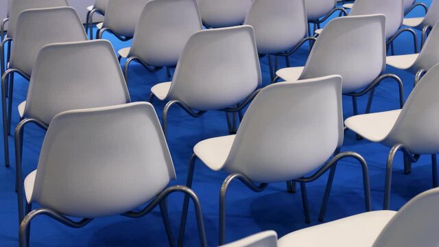 empty white chairs on a blue background in a row