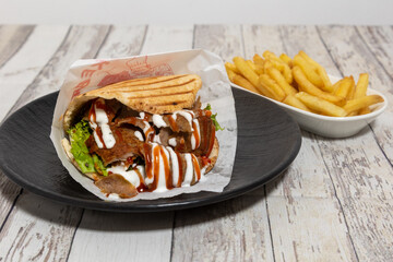 Closeup of delicious gyros with fries on the wooden table.