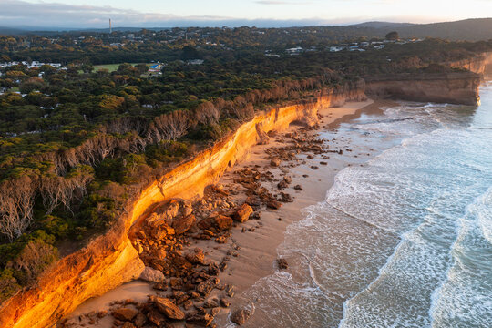 Aerial view of crumbling coastal cliffs catching golden dawn side lighting