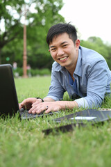 college student with laptop lying on the grass