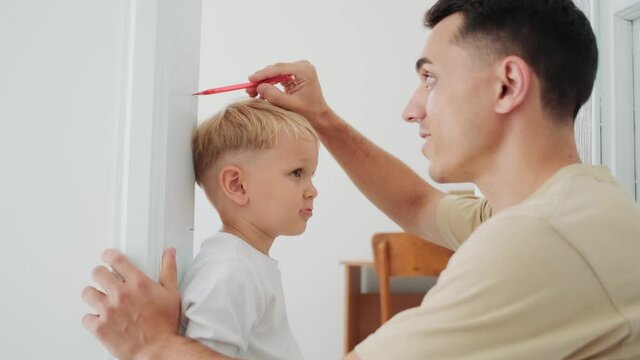 Father measure the height of his little son at home