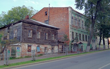A street with old historical buildings in a provincial city of Russia. Wooden residential dilapidated building built in the 19th century