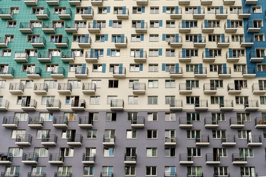 The facade of a multi-apartment new residential building with balconies and windows, painted in 3 colors.