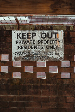 Keep out, private property sign on an old brick wall in a car port.