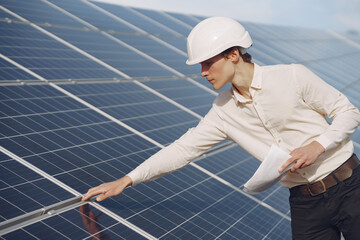 Businessman in a white helmet near solar battery