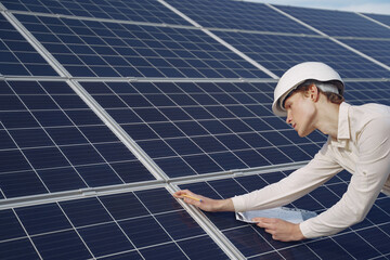 Businessman in a white helmet near solar battery