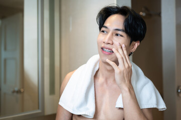 Fototapeta premium Asian handsome young man applying cream for skin care on face