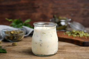 Tasty tartar sauce in glass jar on wooden table