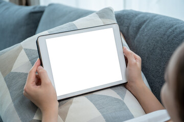 Isolated with clipping path on mockup tablet screen, woman using a tablet while relaxing or sitting on sofa in living room.