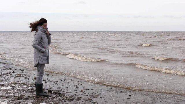 A Woman Looks at the Foamy Waves. Windy Autumn Day at the Shore of Lake Ilmen.