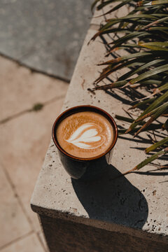 Heart latte coffee art in ceramic cup on a marble tile.