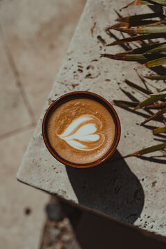 Heart latte coffee art in ceramic cup on a marble tile.
