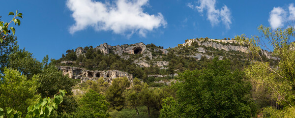 Fototapeta na wymiar Mountain cliffs with caves in Fontaine-de-Vaucluse, Provence, France