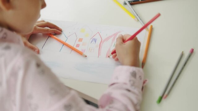 A close-up view of a kid drawing using pencils in the modern art school
